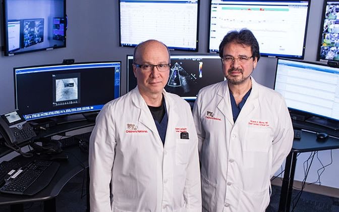 Two members of the Tele-Cardiac team stand in front of monitors in the ICU.