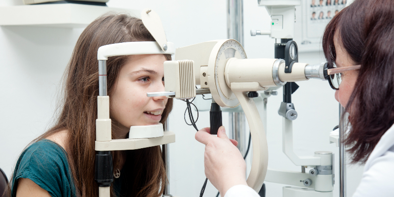 eye doctor examines girl's eyes