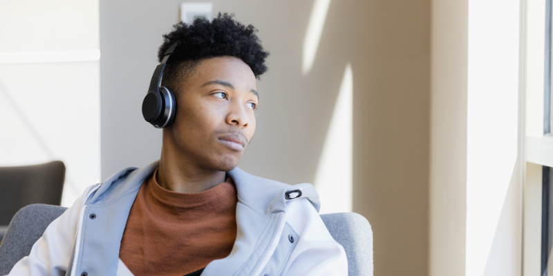 Sad teenaged boy with headphones on and looking out window.