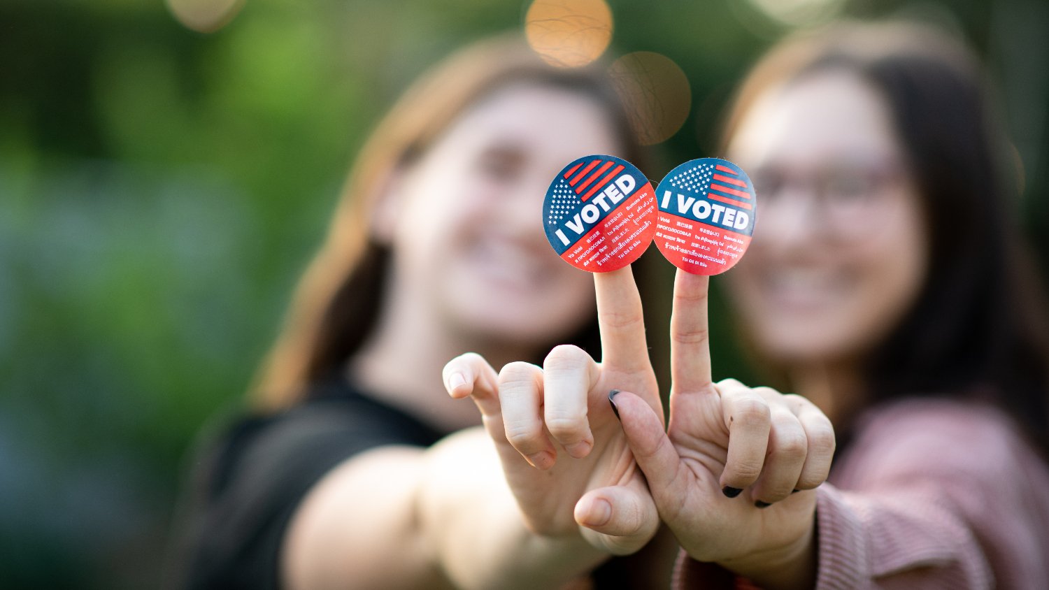 two young women with voting stickers