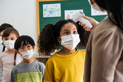 A group of children line up to have their temperature taken at school