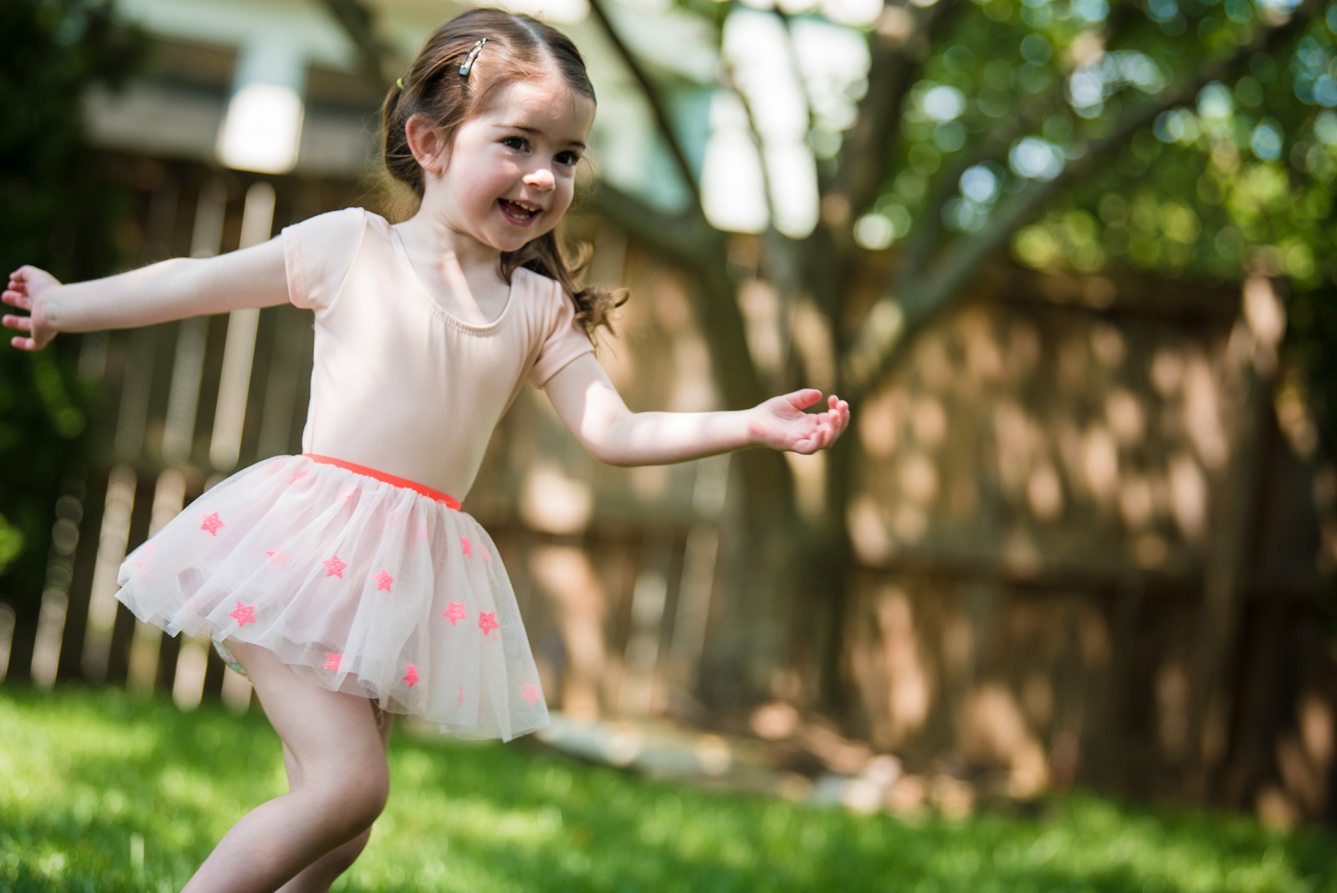A girl in pink dress playing outside. 