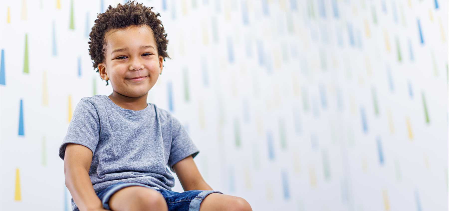 Toddler sitting on exam table smiling.