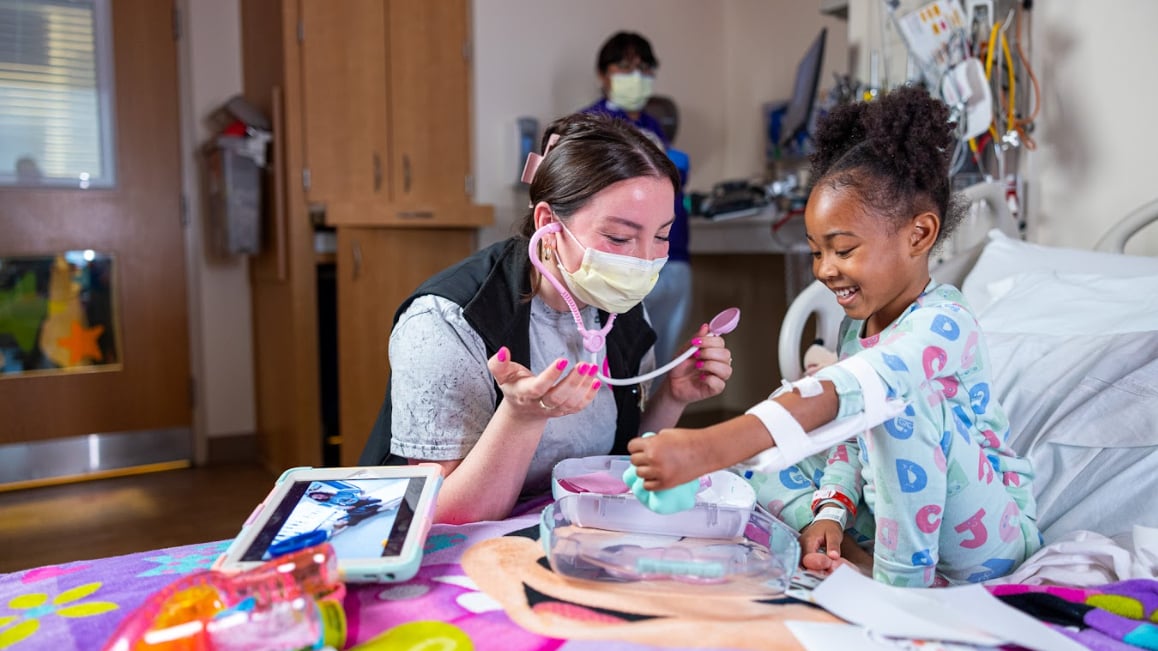 Child life specialist plays pretend with young patient