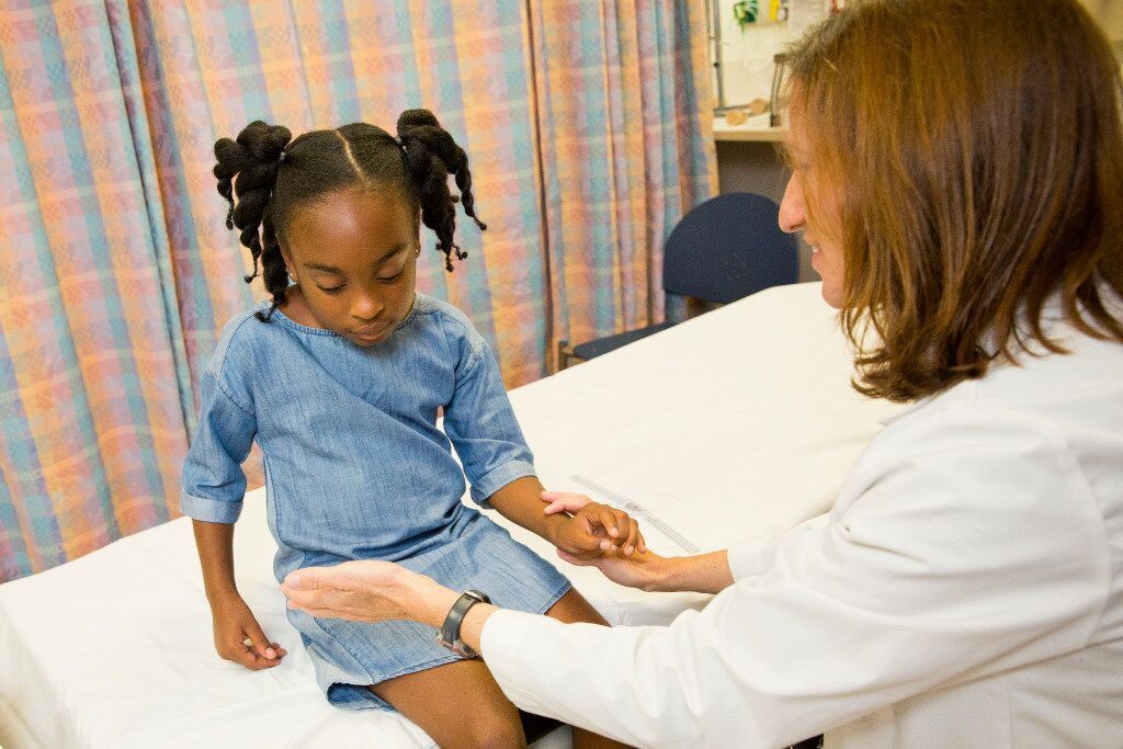 Nurse practitioner in the Hand Program in the Division of Orthopaedics Surgery and Sports Medicine measures female patient's arm.