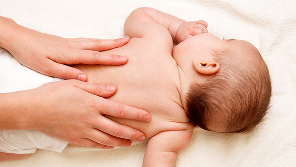Infant on belly with someone's hands on their back