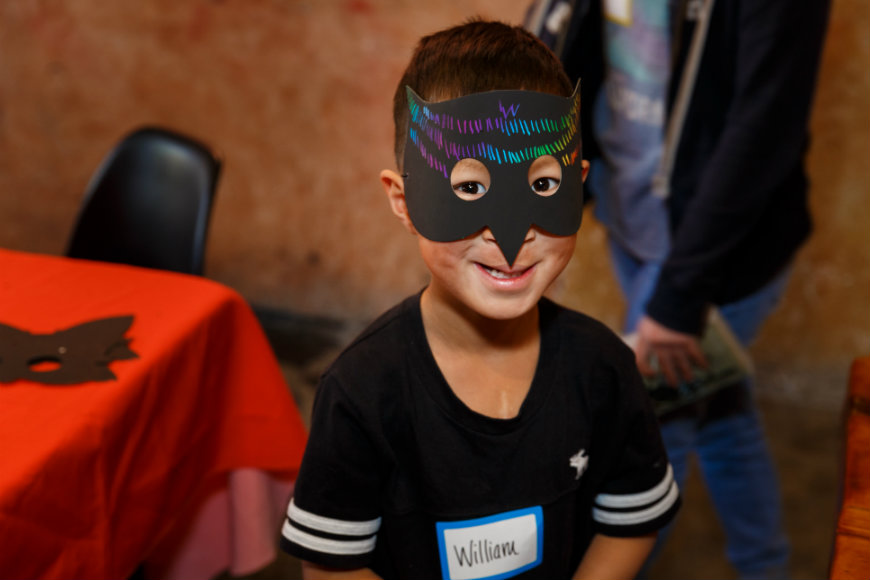 Little man with a mask smiles at craniofacial party.