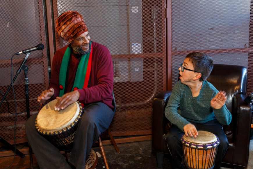 Boy and man play drums together at craniofacial party. 