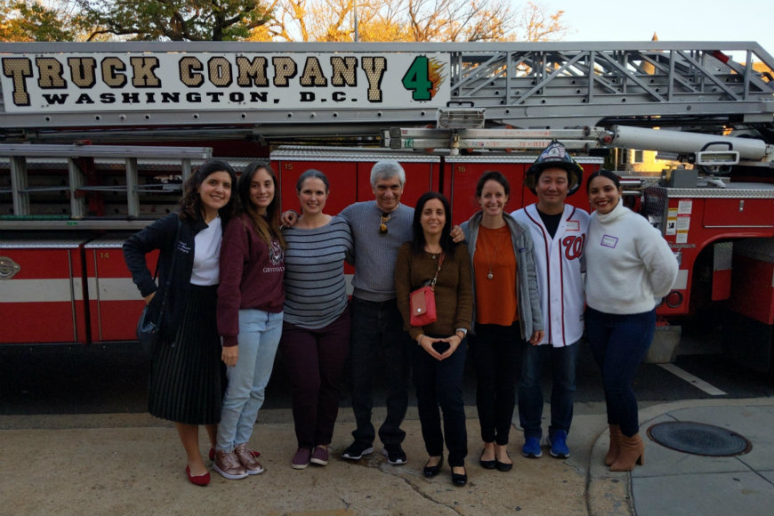 Children's National staffers and adult volunteers smile in front of fire truck at craniofacial party.