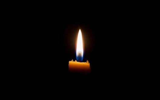 A single candle burning in a darkened room