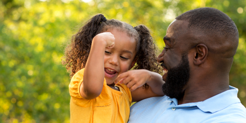 dad with little girl showing her muscles