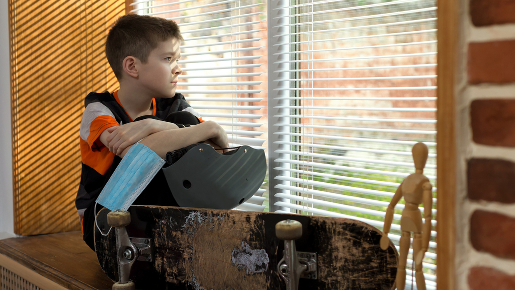 boy with skateboard looks out window