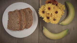 Oatmeal Banana Bread on a white plate next to bananas and sunflowers