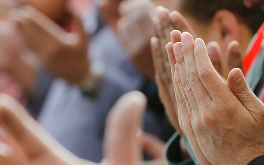 The hands of Muslim men lifted in prayer