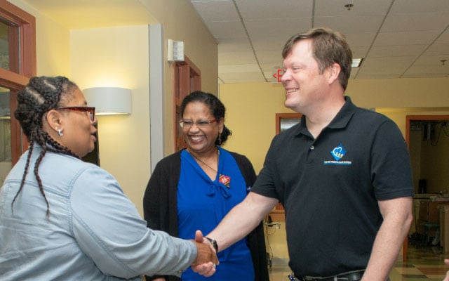 Male provider shaking a woman's hand while another woman smiles in the background