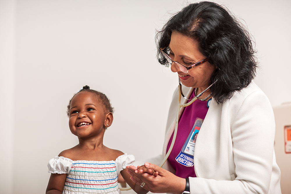 A provider holding a little girl's hand.