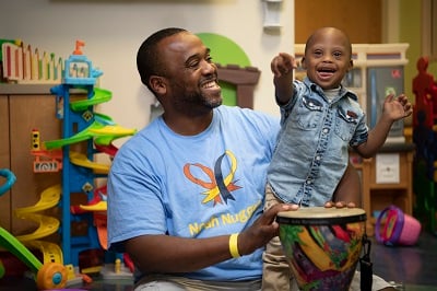 Noah points and smiles in a play room