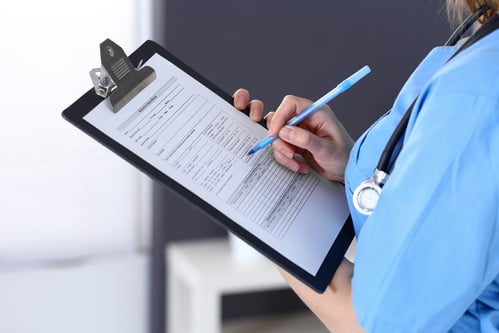 Medical worker writing on a clipboard