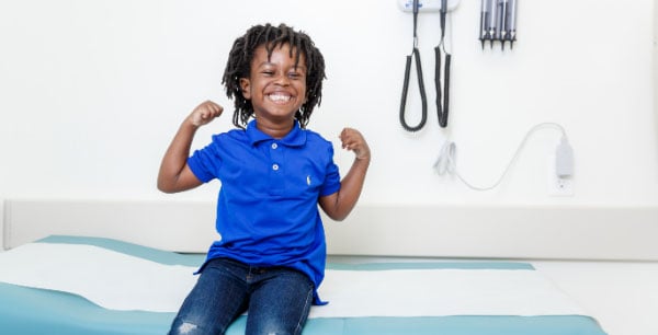 Young boy sitting on exam table at doctors office smiling