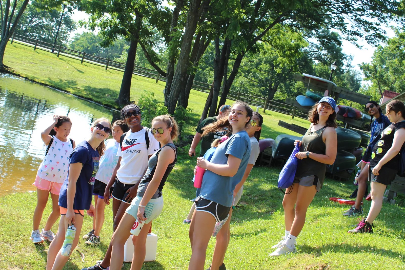 Girls gather near a pond while at a summer camp