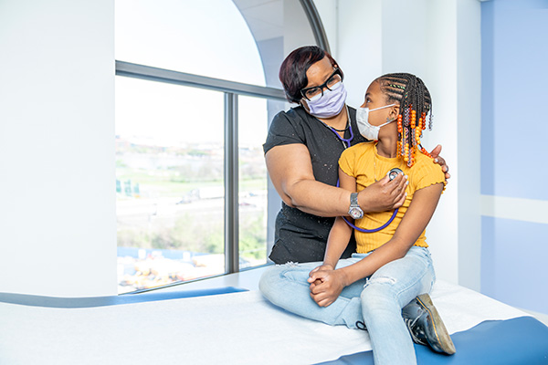 A provider listening to a girl's heart.