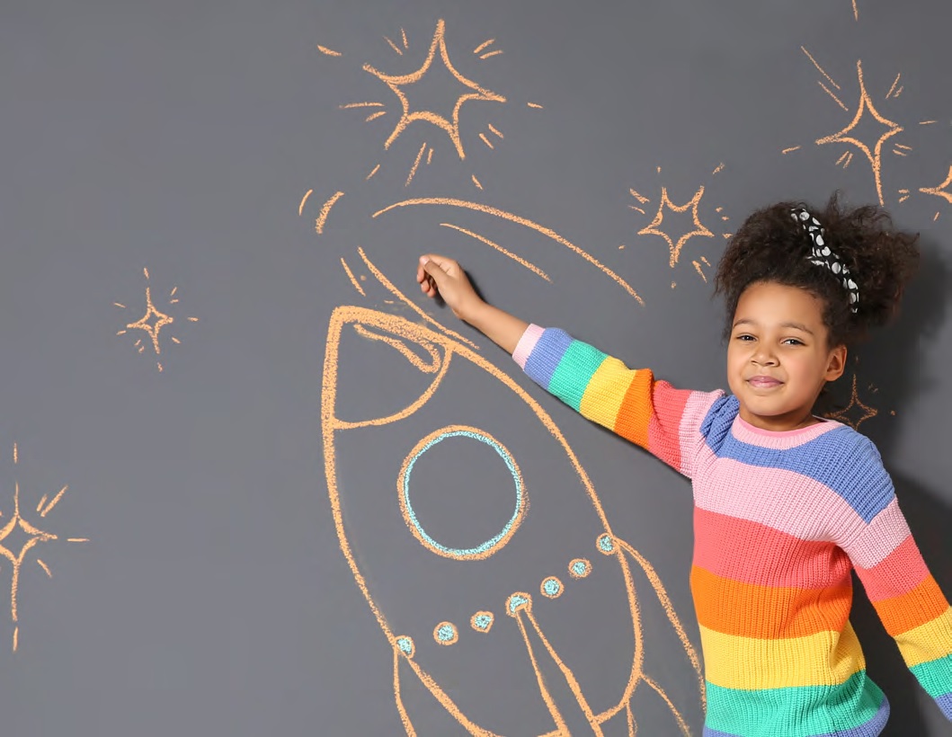 Girl drawing rocket ship on chalk board