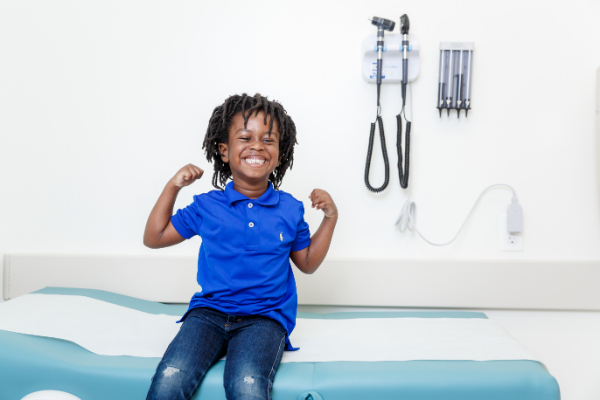 Smiling boy in exam room with arms up