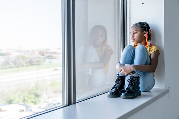 A teen girl looking out the window.