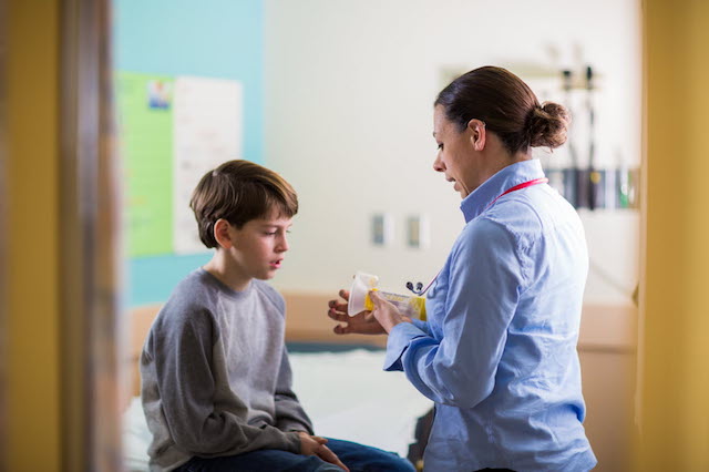 Healthcare Provider Handing a Inhaler to a Boy.