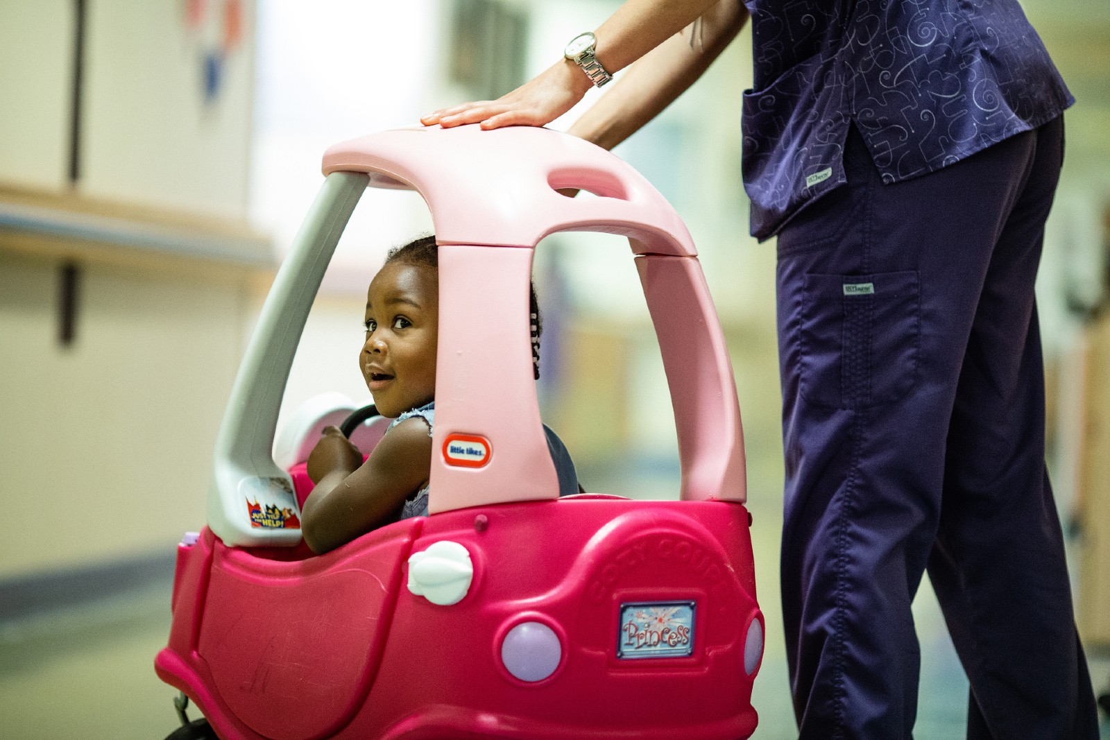 A Child in a Pink Ride-on Car.
