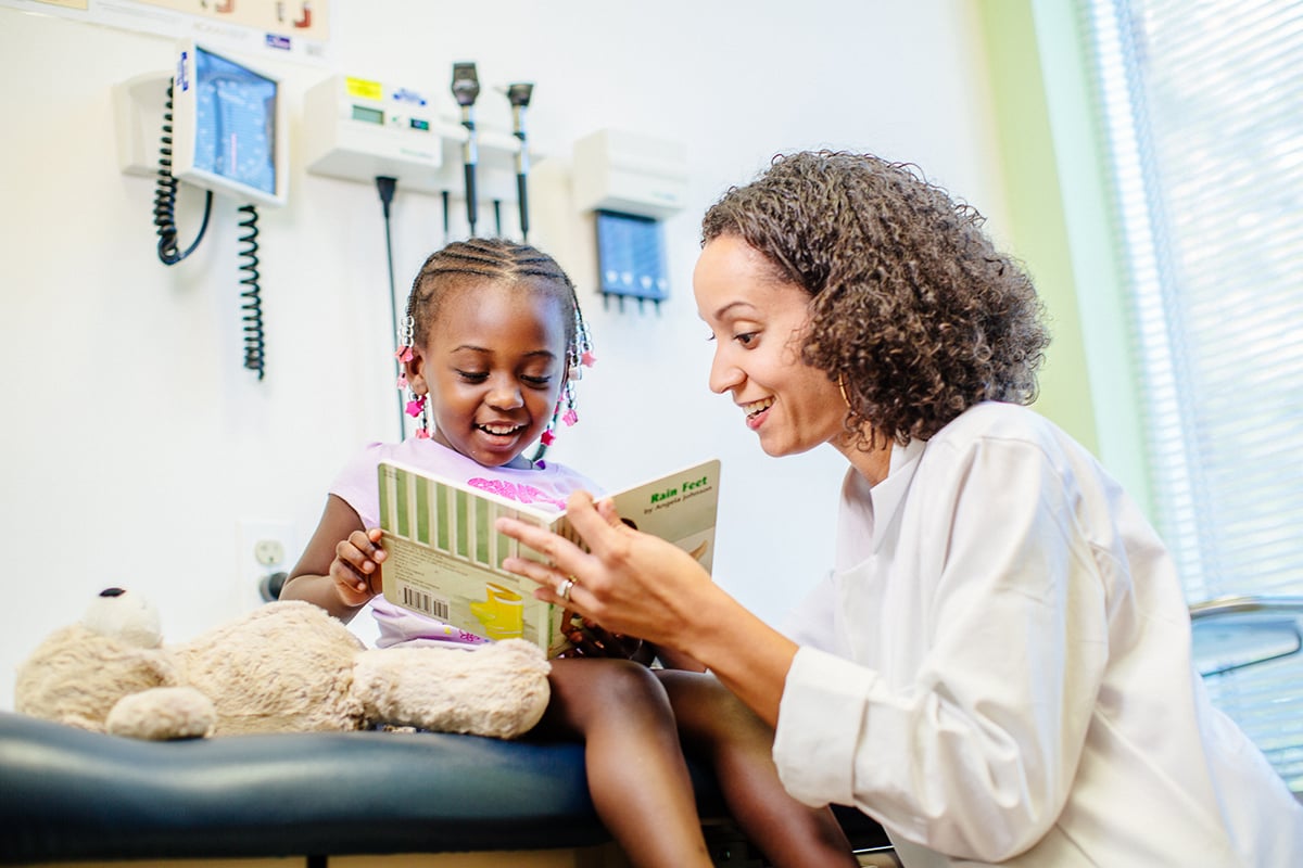 Female provider showing a little girl patient a book