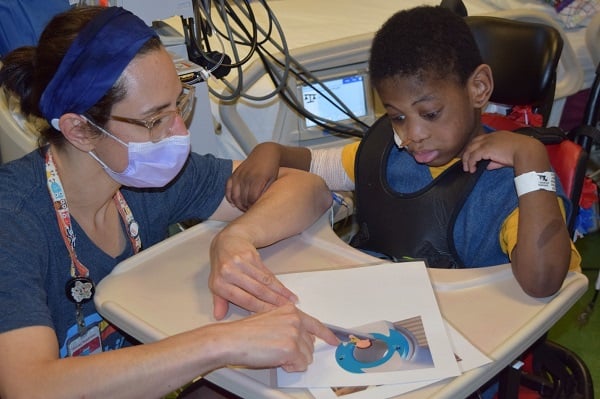 Child life specialist talking with young boy in wheelchair