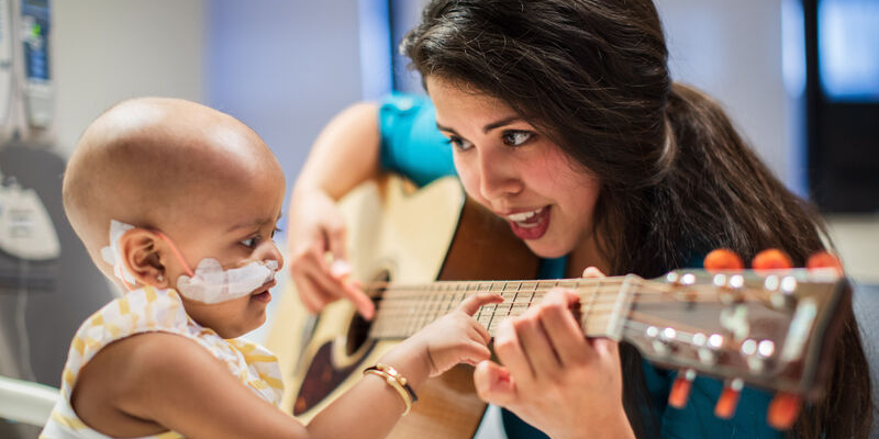 guitar player plays for baby patient