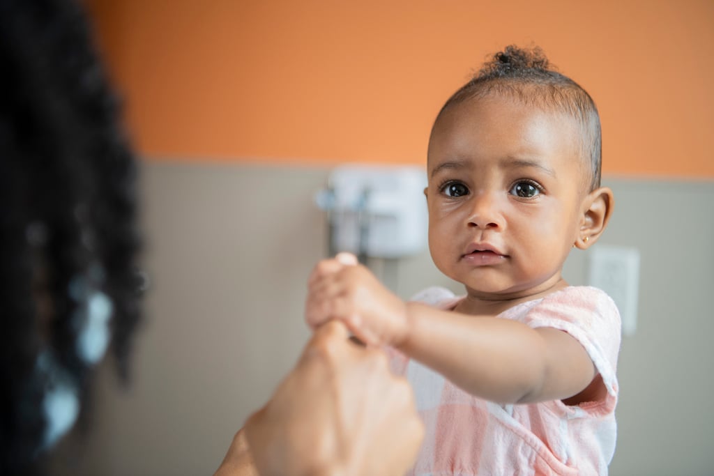 Baby holding onto adult's finger