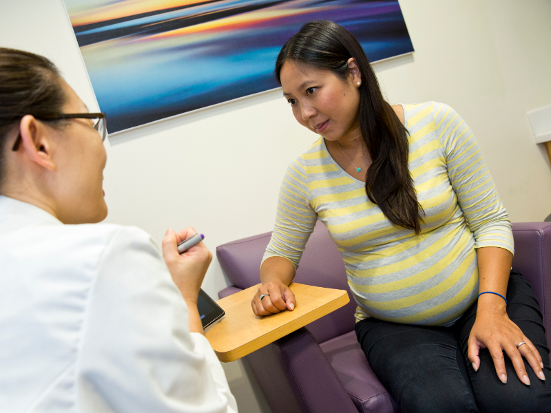 pregnant woman speaks with doctor