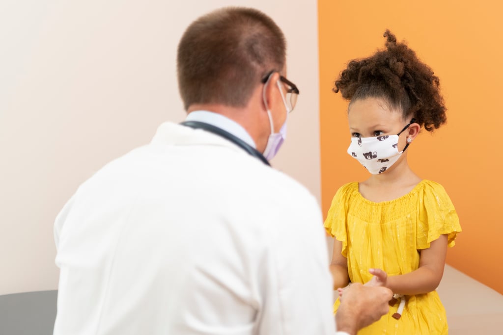 Child wearing mask in exam room on table