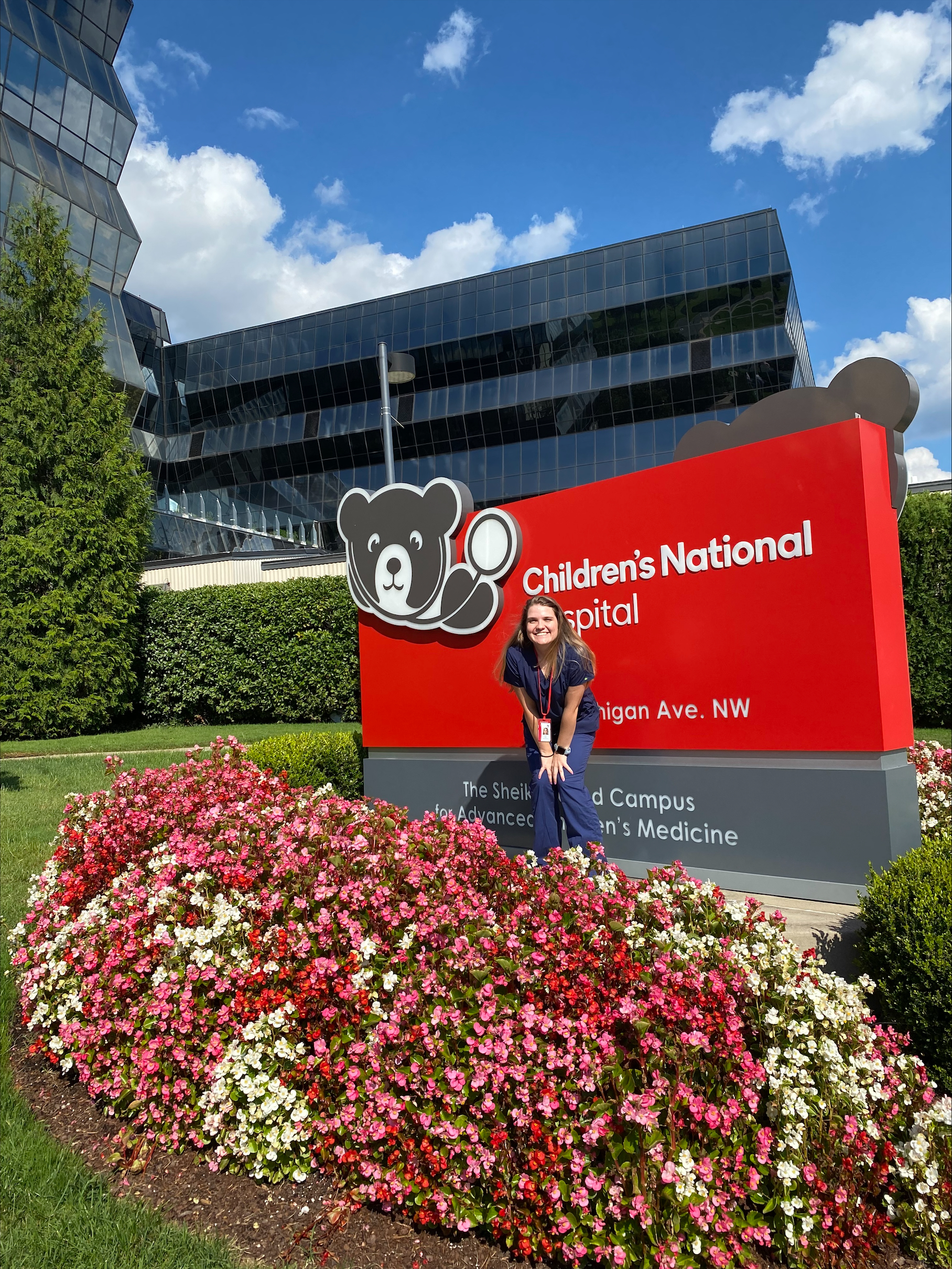 Laura Barrett in front of the main entrance sign at Children's National Hospital