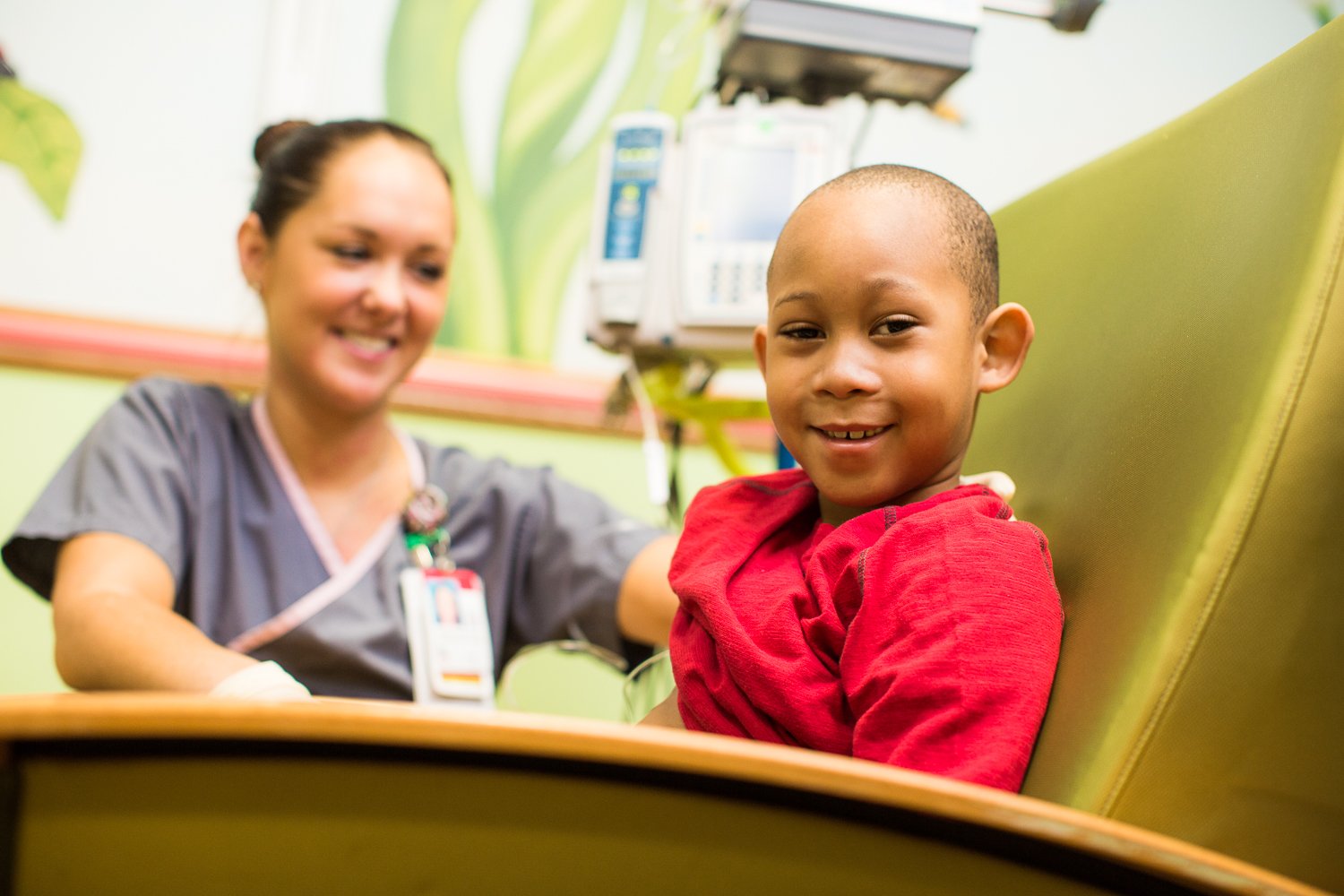 A nurse sitting with a little boy in a red shirt