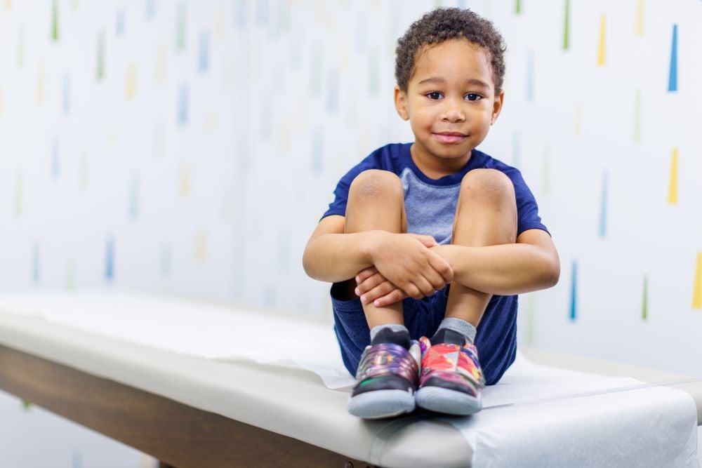 A young boy sits on an exam table in a doctor's office.