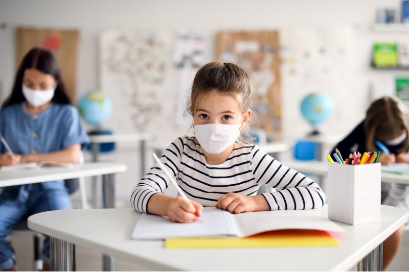 Girl wearing a mask in the classroom while doing school work