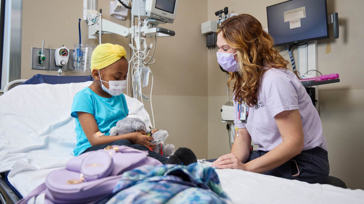 Child Life Specialist uses a therapy doll to demonstrate medical treatments and procedures to a patient