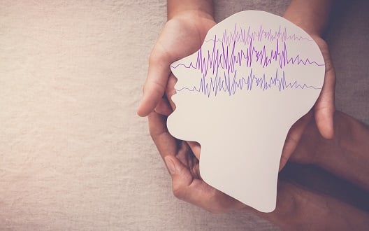 Hands holding paper head with illustrated brainwaves