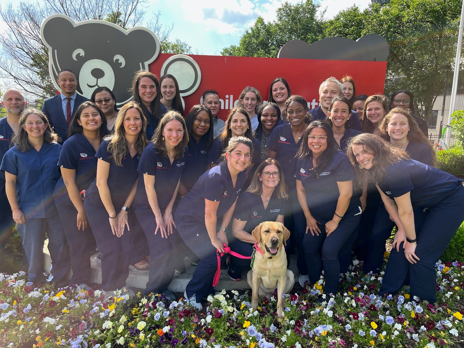 Pediatric Colorectal & Pelvic Reconstruction team (and a dog) pose in front of a Children's National sign.