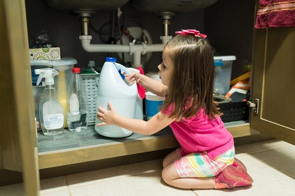 Little girl reaching for bleach container
