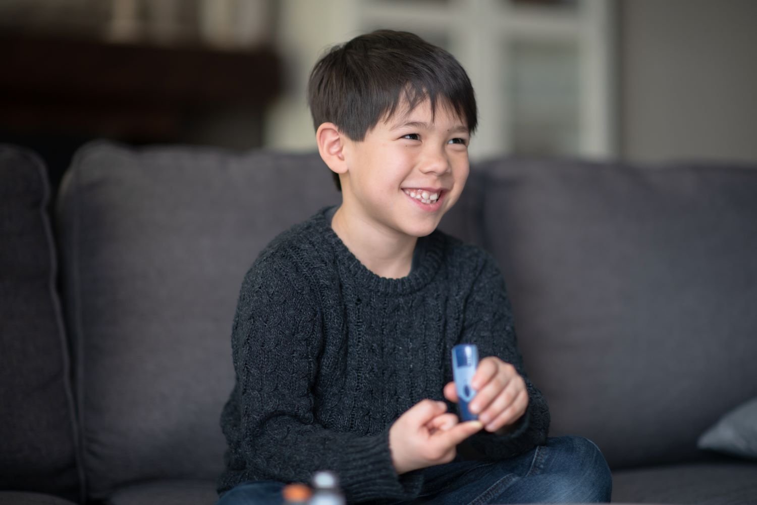 Photograph of smiling boy testing his blood sugar for diabetes