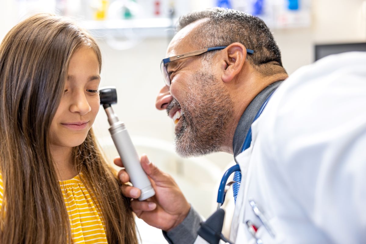Otolaryngologist examining young girl's ear