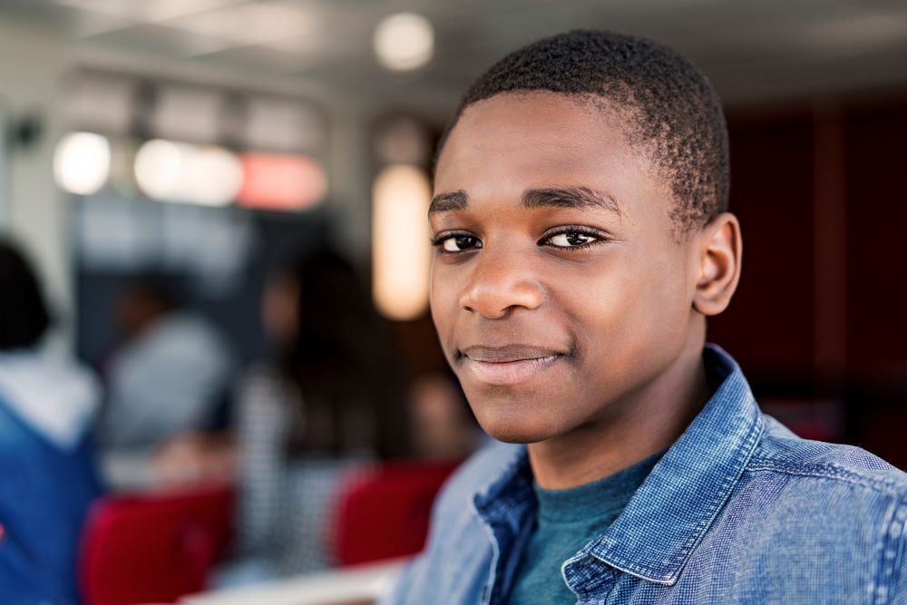 A teenage boy in a denim shirt with a soft smile