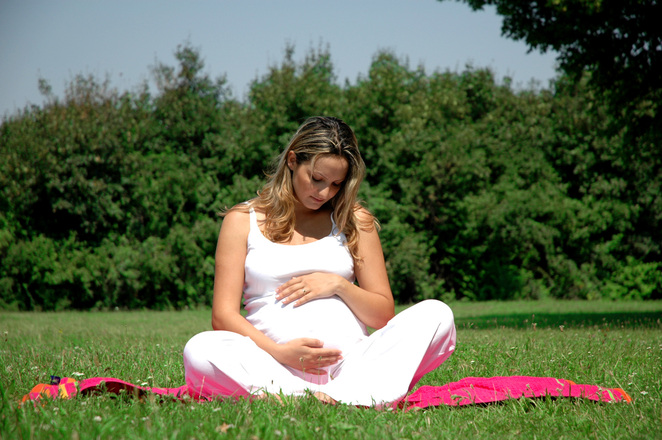 Pregnant woman sitting on a blanket on the grass
