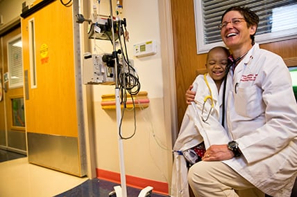 female doctor and patient share a hug in a hospital hallway