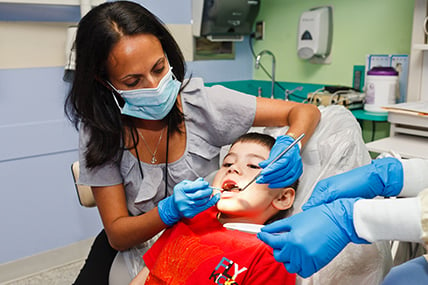 female dentist checks teeth of young patient